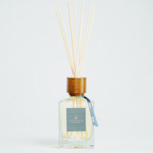 Fragranza Oud Rose. Diffusore a bastoncini Euthalia Fragrances, con flacone in vetro trasparente. Il tappo in legno e i bastoncini completano il design elegante, ideale per profumare ambienti con una fragranza raffinata e di lunga durata.