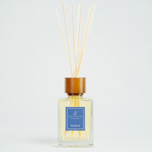 Fragranza Ficus Apuliae. Diffusore a bastoncini Euthalia Fragrances, con flacone in vetro trasparente. Il tappo in legno e i bastoncini completano il design elegante, ideale per profumare ambienti con una fragranza raffinata e di lunga durata.