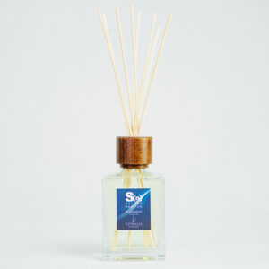 Fragranza Salone Nautico - Blue Essence. Diffusore a bastoncini Euthalia Fragrances, con flacone in vetro trasparente. Il tappo in legno e i bastoncini completano il design elegante, ideale per profumare ambienti con una fragranza raffinata e di lunga durata.