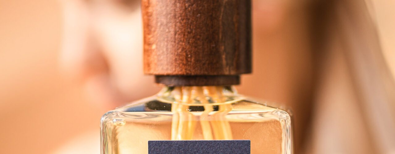 Diffusore di profumi Euthalia Fragrances Nefertiti Oud con bastoncini di legno su tavolo di legno, sfondo beige chiaro, design elegante e raffinato. Chi siamo. Il piacere delle vacanze - holidays pleasure
