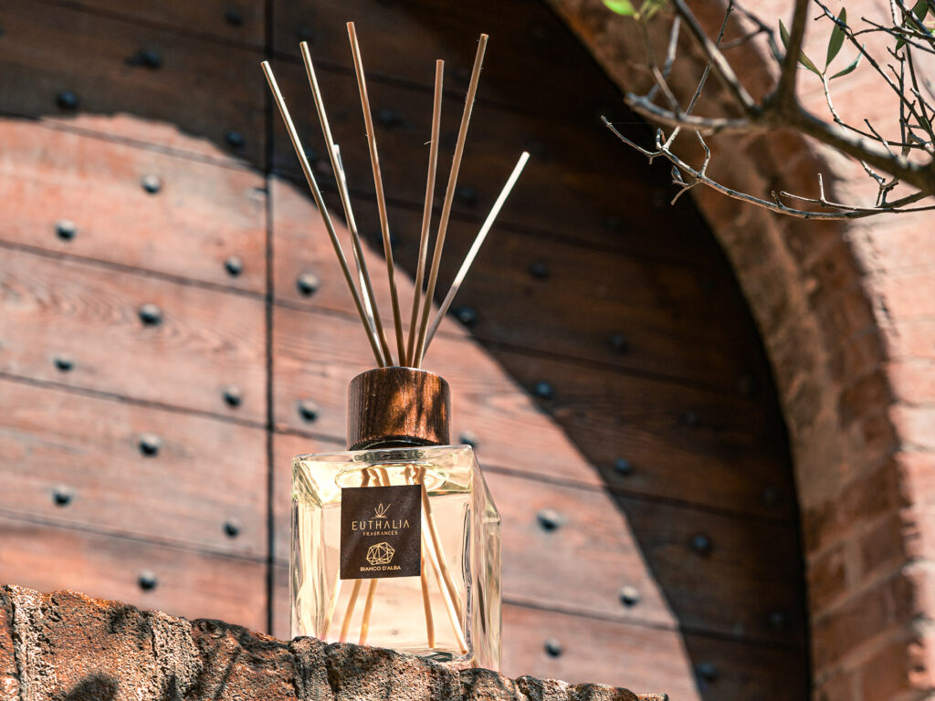 Diffusore di profumo ambiente Euthalia Fragrances Bianco d’Alba fotografato all’esterno con dettagli di legno e mattoni, immagine evocativa dell’autunno e delle sue atmosfere calde e raffinate. Autumn vibes.