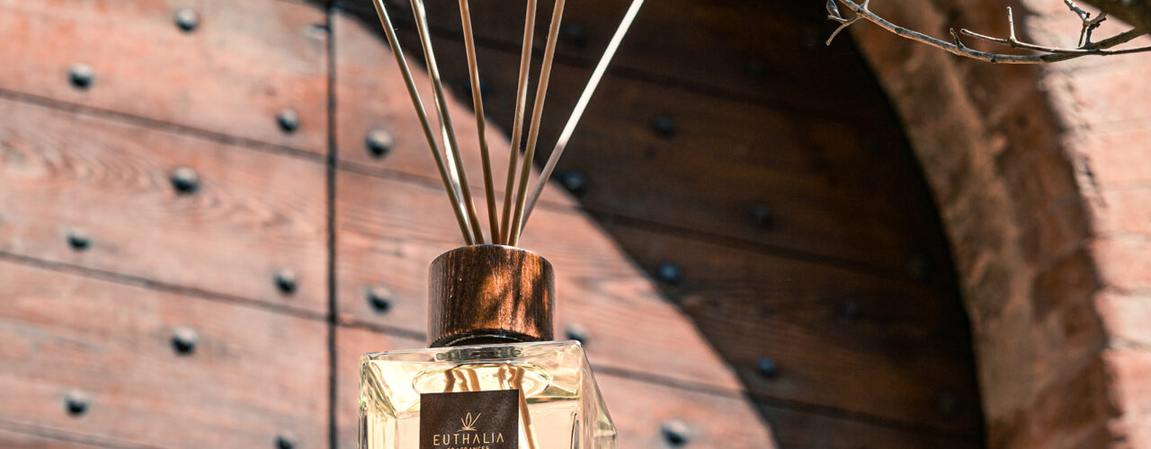 Diffusore di profumo ambiente Euthalia Fragrances Bianco d’Alba fotografato all’esterno con dettagli di legno e mattoni, immagine evocativa dell’autunno e delle sue atmosfere calde e raffinate. Autumn vibes.