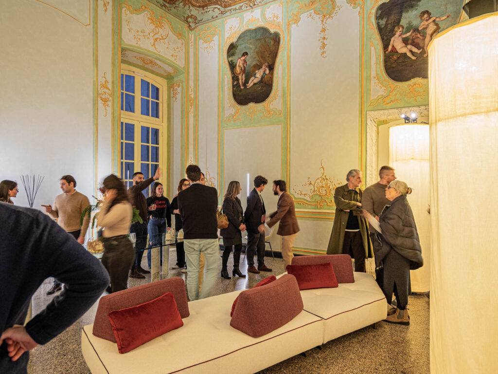 Immagine dell’inaugurazione del nuovo show-room Euthalia Fragrances nel salone affrescato di Palazzo Cosmo Centurione a Genova, con ospiti che interagiscono tra installazioni luminose e ambientazione storica. Image of the inauguration of the new Euthalia Fragrances showroom inside the frescoed hall of Palazzo Cosmo Centurione in Genoa, with guests interacting among lighting installations and the historic interior.