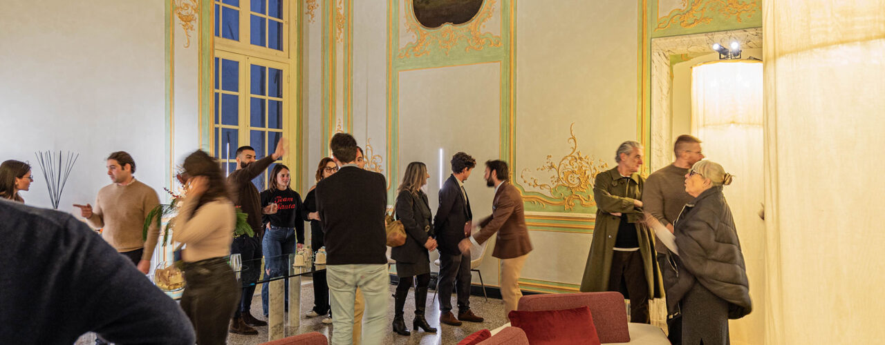 Immagine dell’inaugurazione del nuovo show-room Euthalia Fragrances nel salone affrescato di Palazzo Cosmo Centurione a Genova, con ospiti che interagiscono tra installazioni luminose e ambientazione storica. Image of the inauguration of the new Euthalia Fragrances showroom inside the frescoed hall of Palazzo Cosmo Centurione in Genoa, with guests interacting among lighting installations and the historic interior.