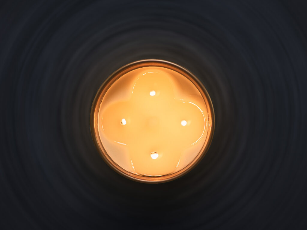 Candela profumata Euthalia Fragrances accesa, dettaglio della cura della candela per una combustione corretta e un’atmosfera elegante in casa. Euthalia Fragrances scented candle lit, a detail of candle care for proper burning and an elegant atmosphere at home.